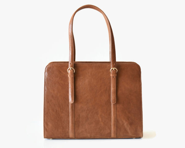 A caramel brown leather laptop bag with two handles and a detachable shoulder strap.