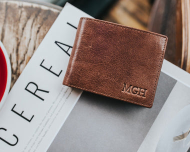 Full grain leather men's wallet with a hot stamped monogram on the front on a Cereal journal